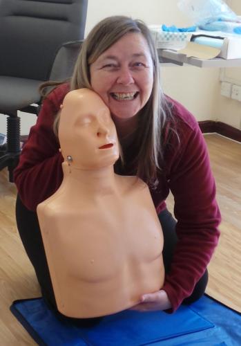 Smiling Carer holding CPR dummy.